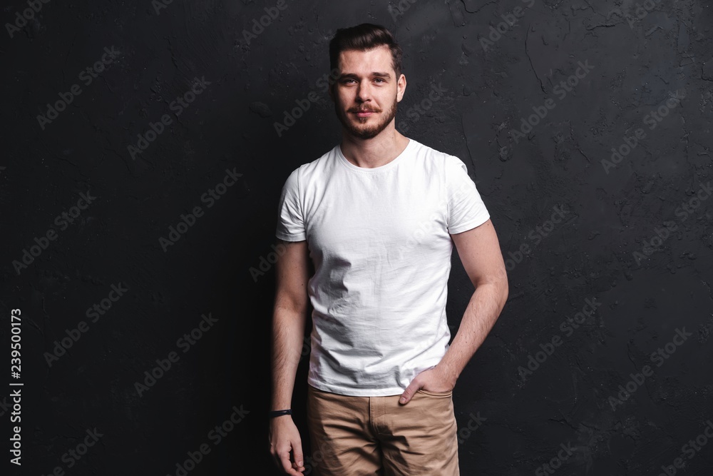 young fashion man posing for the camera on black background