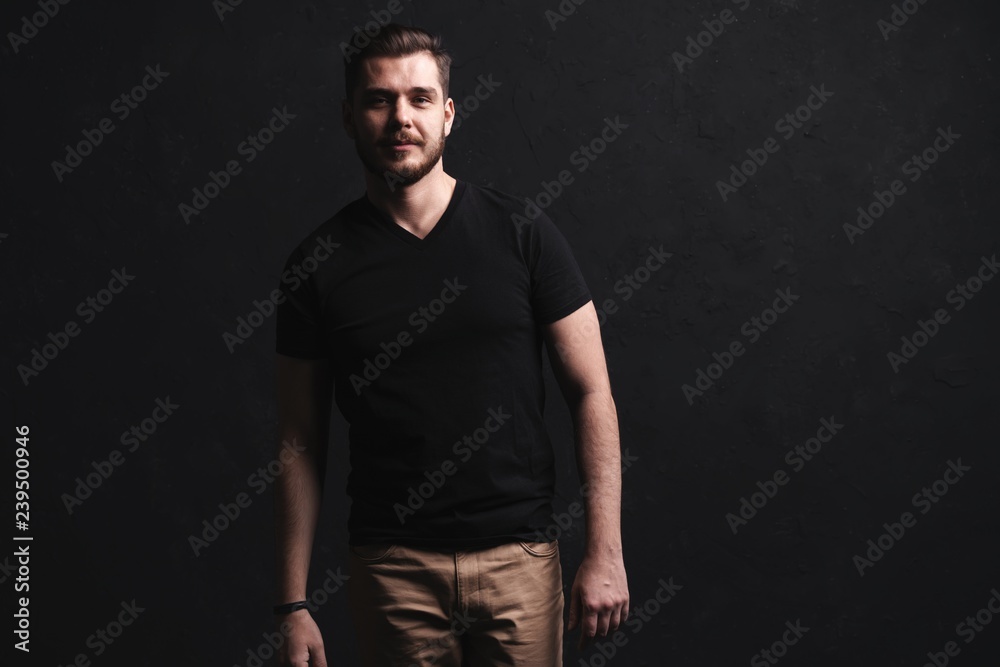 young fashion man posing for the camera on black background