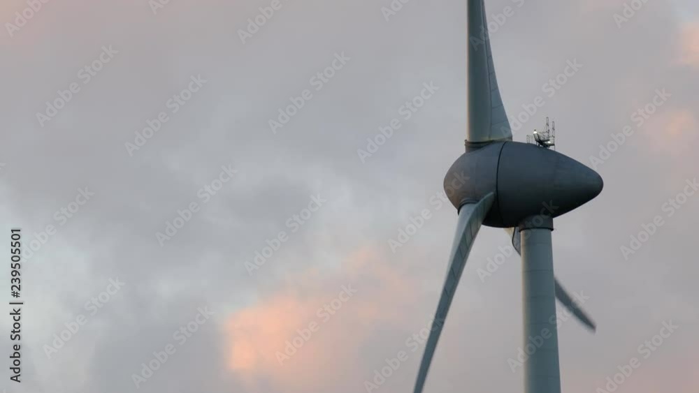 Wind turbine with turning blades in the wind in an offshore windpark during sunset. Wind turbine with turning blades in the wind in an offshore windpark during sunset.
