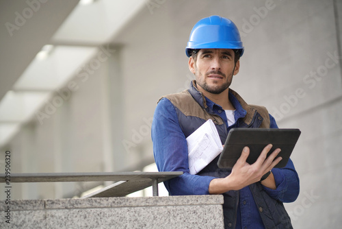 Handsome building expert in hardhat outdoors with tablet and blueprint © goodluz