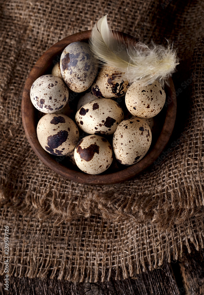 Quail eggs in a wooden plate on the old background. Rustic style on dark background. Quail eggs in a wooden plate on the old background. Rustic style on dark background.