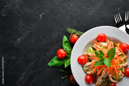 Salad with chicken and fresh vegetables on a black background. Free space for your text. Top view.