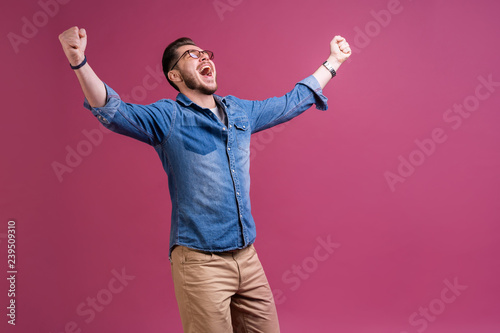 Принти на полотні Portrait of a satisfied young man celebrating success isolated over pink background