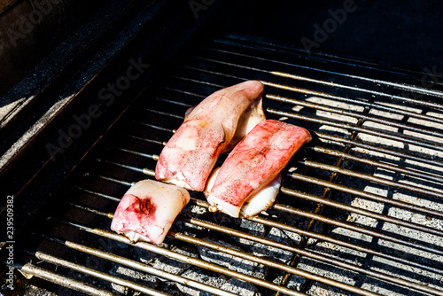 Grilling squid or cuttlefish on a coal barbecue grill.