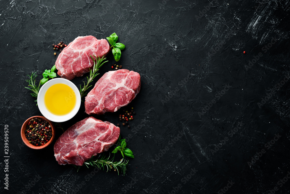 Raw steak. Meat with spices and herbs. On a black stone background. Top view. Free copy space.