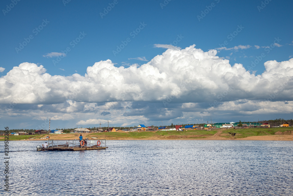 Rural landscape at summer cloudy day. Ferry on the Amga River in the Yakut village of Chakyr, Yakutia, Siberia, Russia