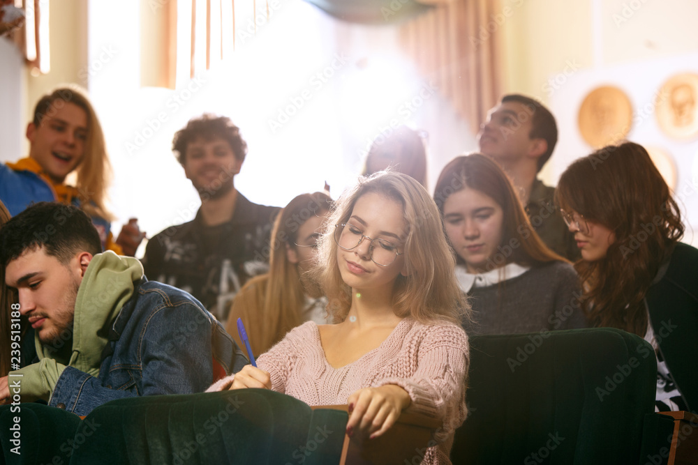 The group of cheerful students sitting in a lecture hall before lesson. The education, university, lecture, people, institute, college, studying, friendship and communication concept