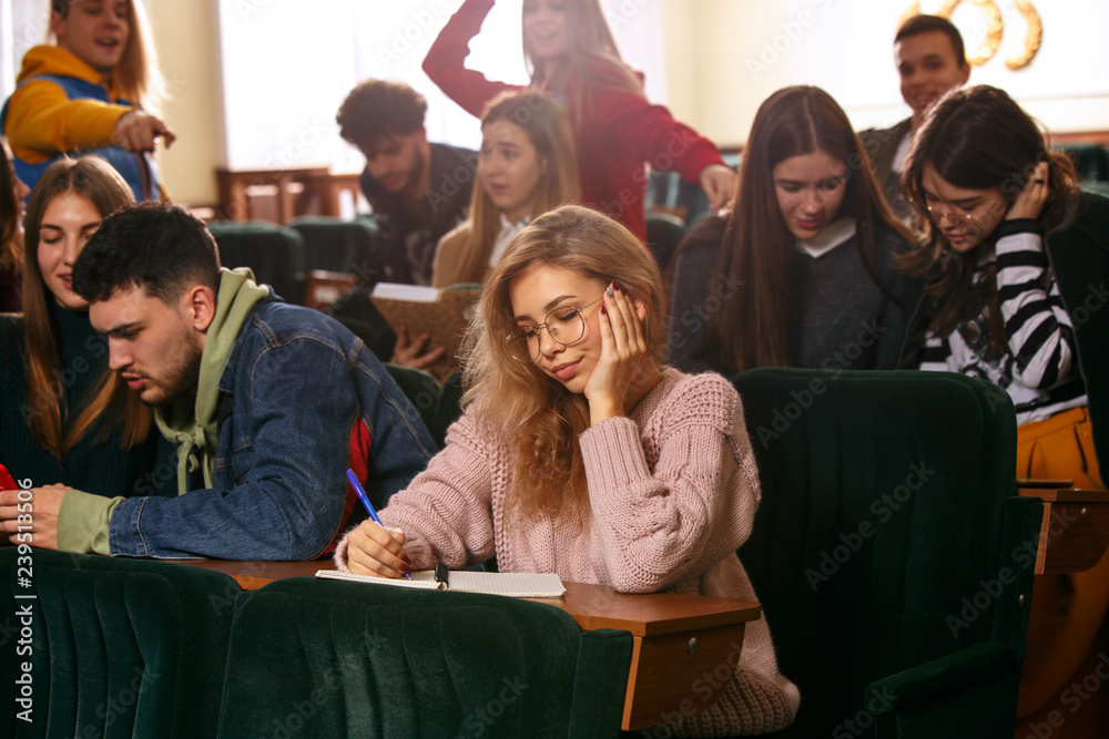 The group of cheerful students sitting in a lecture hall before lesson. The education, university, lecture, people, institute, college, studying, friendship and communication concept