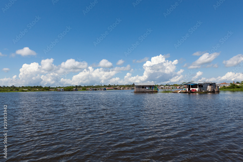 Colorful wooden floating houses on the Rio Negro on sunny summer day with blue sky in the Brazilian Amazon. Manaus, Amazonas, Brazil.