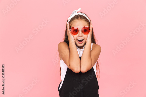 Cheerful little girl wearing dress and sunglasses standing