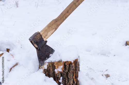 Ax stuck in a log on the background of snow. chopped firewood. Alternative fuel. Atmospheric winter photo
