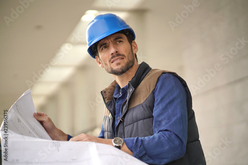 Attractive architect in hardhat checking blueprints outdoors
