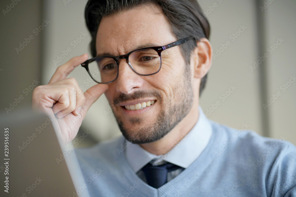 Portrait of attractive man smiling working on laptop wearing glasses Portrait of attractive man smiling working on laptop wearing glasses