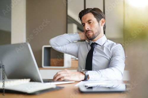 Stressed handsome business man looking at laptop in office