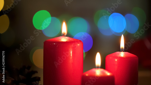 Red candles burning, Christmas lights twinkling on background, miraculous time
