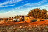Pickup 4x4 car with a tent on the roof on road trip has a stop at a camping rest area in desolate nature landscape in the desert of Kalahari in Namibia, Africa