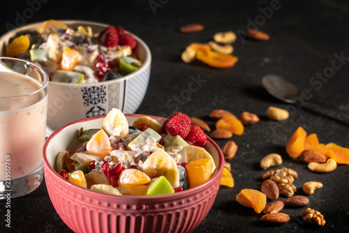 Porridge with berries and nuts in a bowl with yogurt for healthy breakfast on rustic wooden background. top view