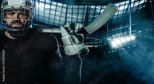Photography Ice Hockey player in the helmet and gloves on stadium with stick.