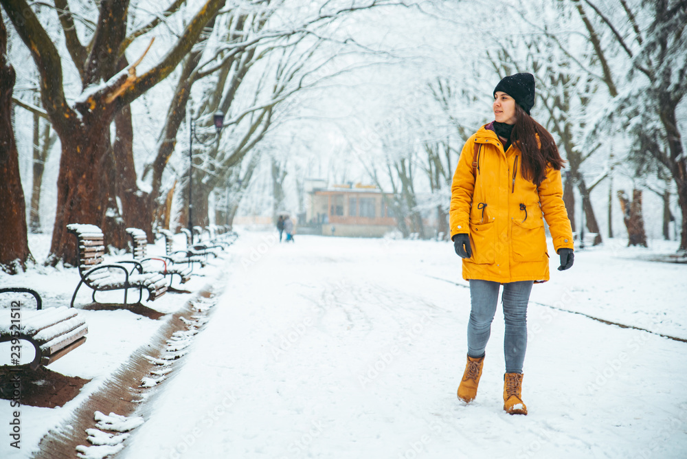 woman walking by snowed city park. winter beauty
