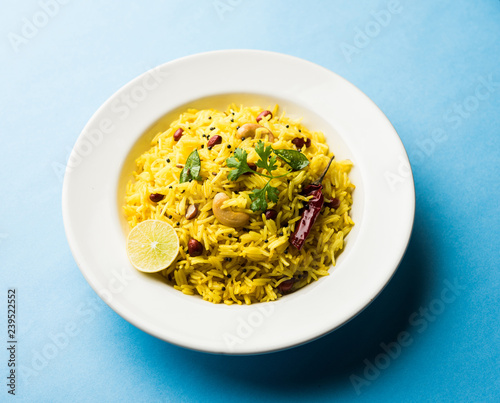Lemon Rice is a South Indian turmeric rice or maharashtrian recipe called fodnicha bhat using leftover rice garnished with nuts curry leaves and lemon juice, selective focus