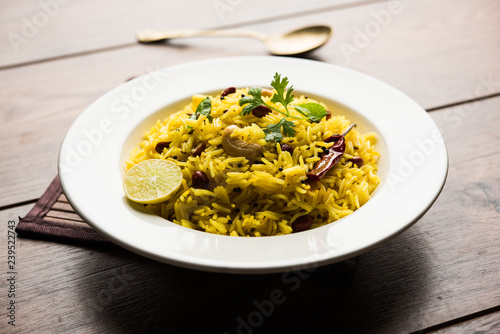 Lemon Rice is a South Indian turmeric rice or maharashtrian recipe called fodnicha bhat using leftover rice garnished with nuts curry leaves and lemon juice, selective focus