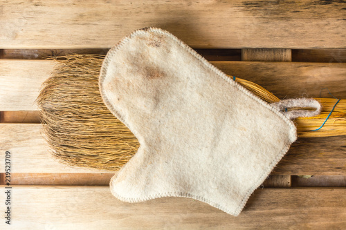 White mitten lies on a yellow broom in a bath