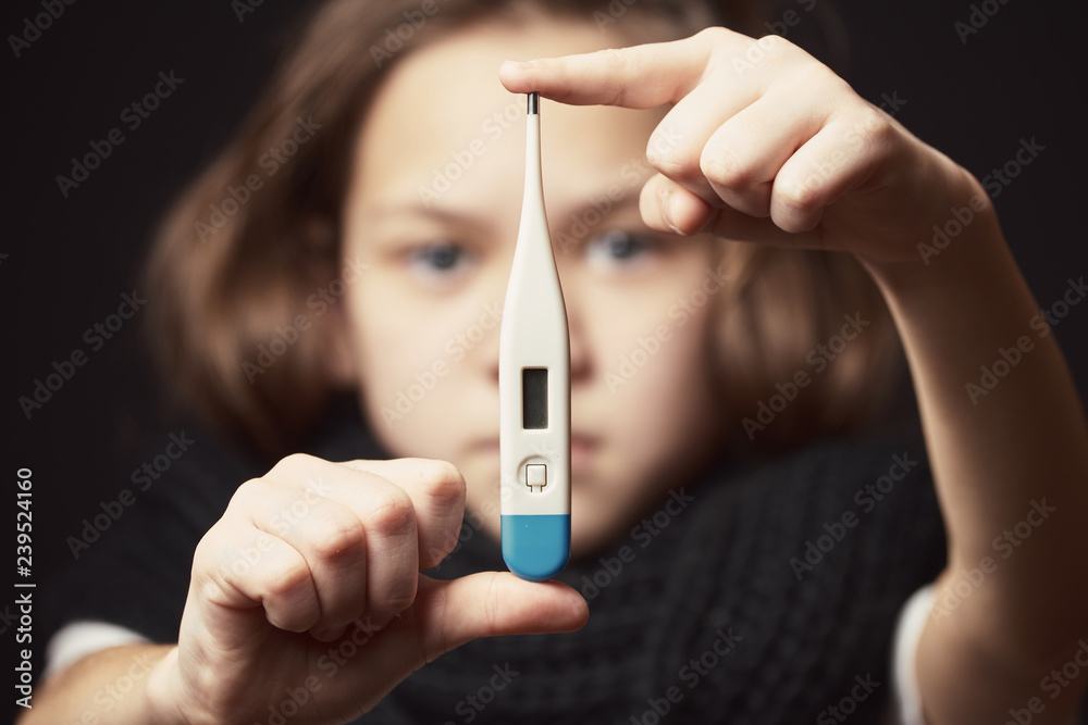 Beautiful girl with black scarf holding white thermometer on her outstretched hands to measure temperature. Beautiful girl with black scarf holding white thermometer on her outstretched hands to measure temperature.