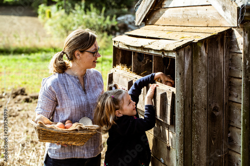 Woman and girl collecting eggs from a chicken house.