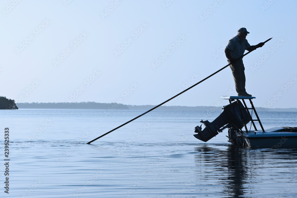 A fly fishing guide poling a flats skiff in search for tarpon and