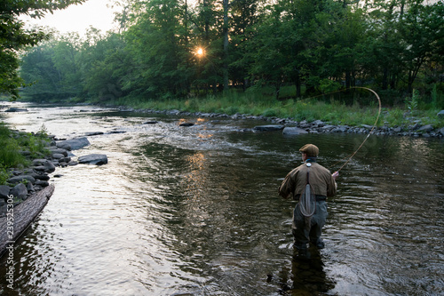 A fly fisherman casting for trout in a small freestone river in northeastern USA. photo