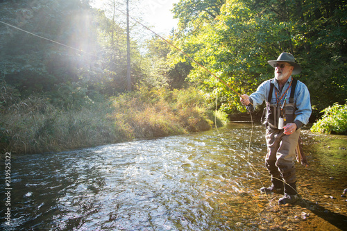A fly fisherman casting for trout in a small freestone river in northeastern USA.