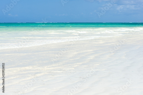 Tropical beach view with waves gently break on the shoreline on a sunny day, Diani, Kenya © James
