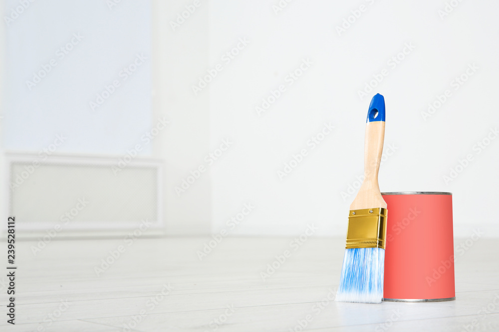 Can of living coral paint and brush on floor indoors. Space for text Can of living coral paint and brush on floor indoors. Space for text