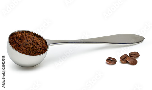 Grinded coffee powder in measuring scoop with beans isolated on white background