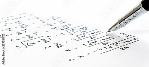 Handwriting of mathematics quadratic equation formula on examination, practice, quiz or test in maths class. Solving exponential equations background concept. photo