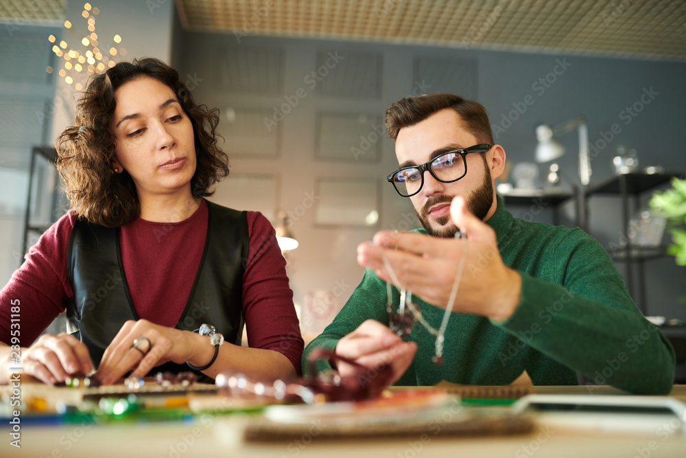 Portrait of handsome male designer working on creative project while sitting at table with female colleague Portrait of handsome male designer working on creative project while sitting at table with female colleague