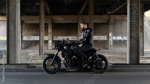 Guy on a black motorcycle motorcycle stay under the bridge photo