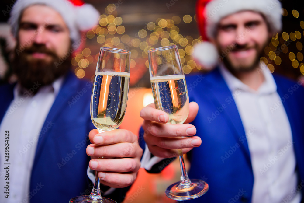 Business people drink champagne at party. Colleagues celebrate new year. Men formal suits and santa hats hold champagne glasses. Cheers concept. New year corporate party. Party with champagne