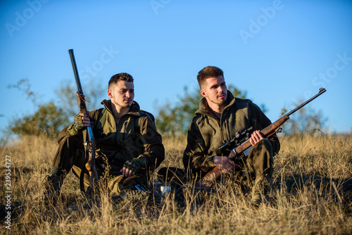 Rest for real men concept. Discussing catch. Hunters with rifles relaxing in nature environment. Hunter friend enjoy leisure in field. Hunters gamekeepers relaxing. Hunting with friends hobby leisure