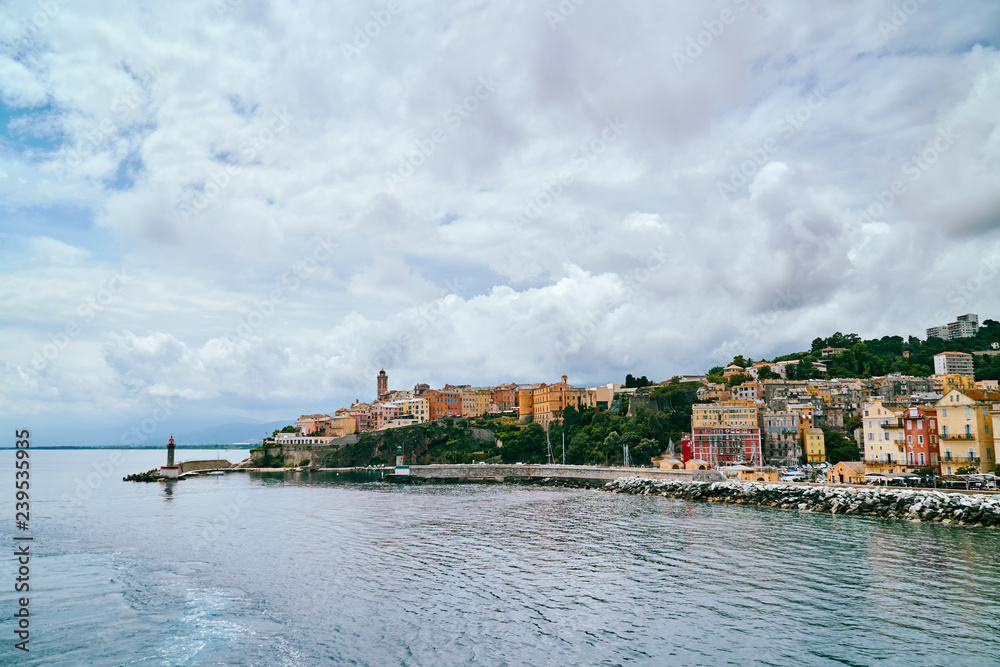 View of small lighthouse in port of Bastia city in Corsica, Corse - view from the sea on cloudy day