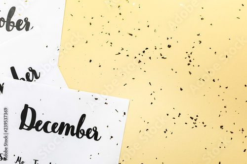 top view of winter calendar and golden confetti on beige background