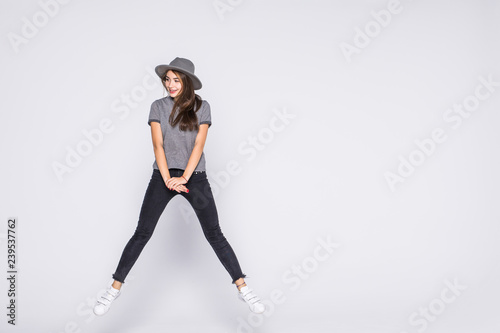 Full length portrait of satisfied american woman wearing jeans and t-shirt jumping isolated over white background