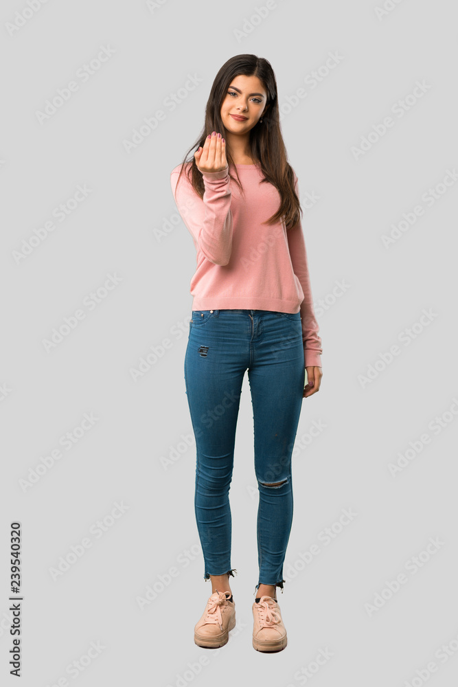 Full body of Teenager girl with pink shirt inviting to come with hand. Happy that you came on isolated grey background Full body of Teenager girl with pink shirt inviting to come with hand. Happy that you came on isolated grey background