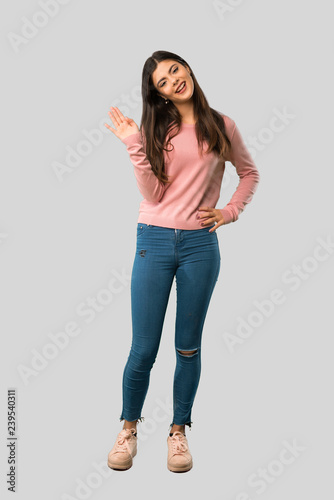 Full body of Teenager girl with pink shirt saluting with hand with happy expression on isolated grey background