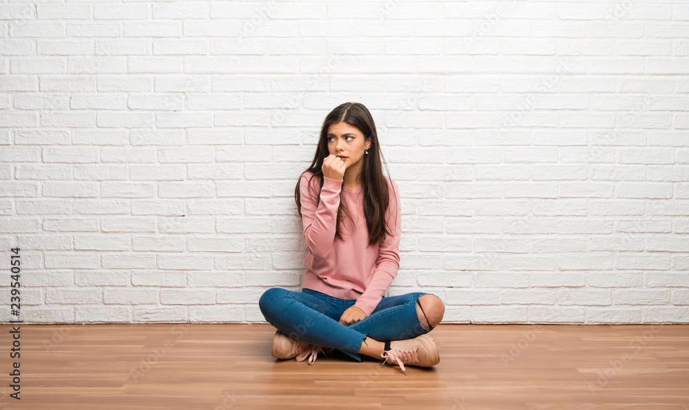 Teenager girl sitting on the floor in a room having doubts Teenager girl sitting on the floor in a room having doubts