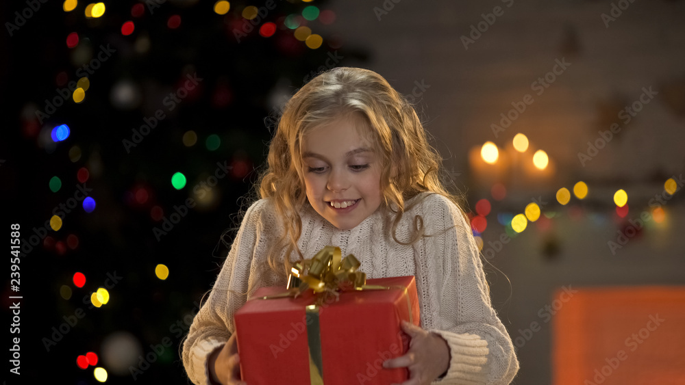 Girl hugging wrapped gift box, long-awaited Christmas present, dreams come true