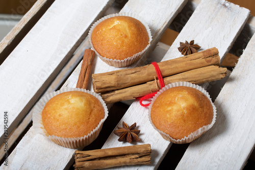 Fresh tasty muffins. Nearby are cinnamon sticks and anise stars. Located on a wooden box.