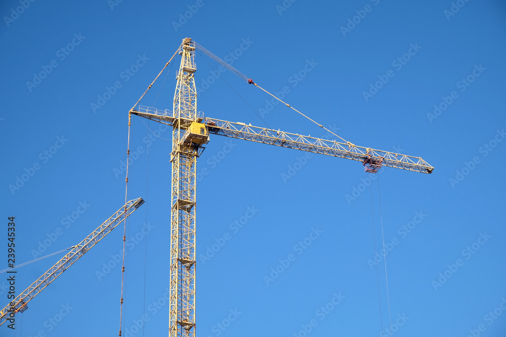Big yellow construction tower crane over clear blue as background, sky horizontal photo Big yellow construction tower crane over clear blue as background, sky horizontal photo