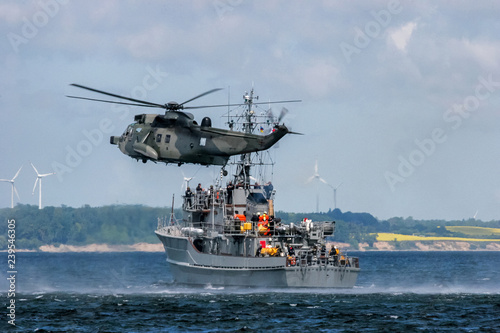 NATO rescue mission in sea with ship and helicopter.
