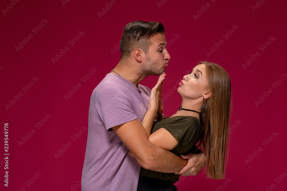 Portrait of outraged displeased woman gesturing to stop with hand while man trying to kiss her on burgundy background Portrait of outraged displeased woman gesturing to stop with hand while man trying to kiss her on burgundy background